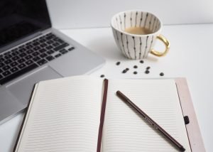 white notebook beside silver macbook pro